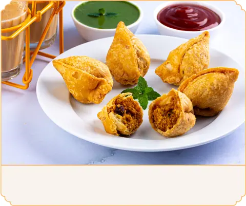 Plate of crispy samosas with green chutney and red sauce