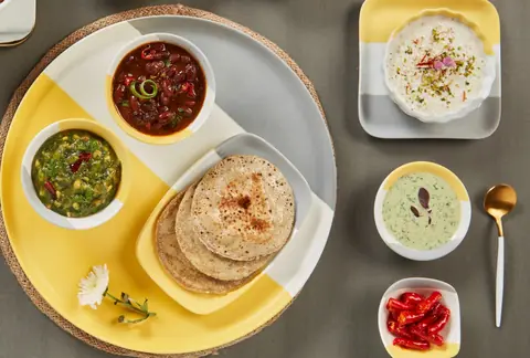 Indian meal with roti, two types of curry, raita, and pickled chilies