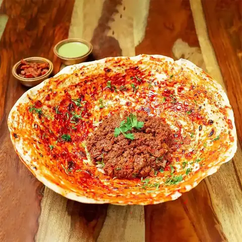 Spiced minced meat curry served in a large bowl with chutneys on the side