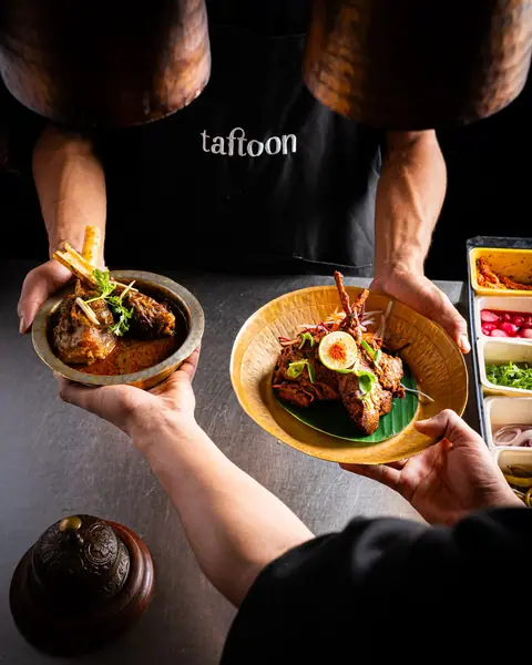 Two plates of Indian meat dishes with garnishes served at Taftoon