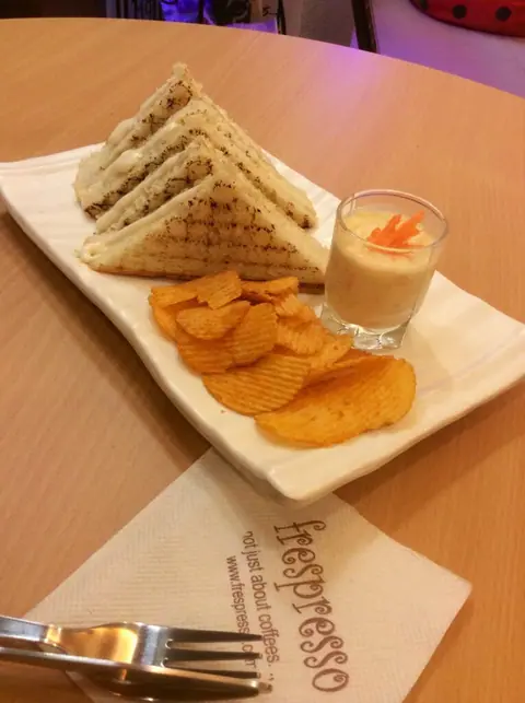 Grilled sandwich with potato chips and a small glass of dip