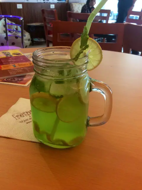 Green mint lemonade in a glass jar with lemon slice and straw