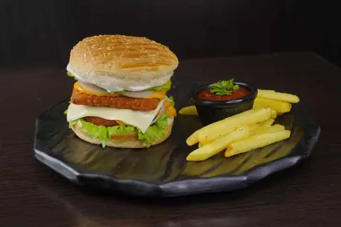 Veg burger with lettuce, cheese, and fries with ketchup on black plate