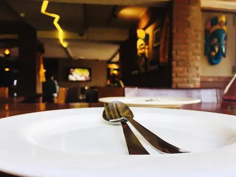 Empty white plate with fork and spoon on table inside restaurant