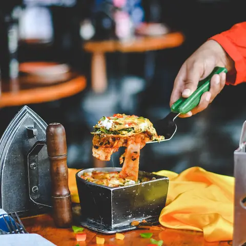 Cheesy baked lasagna slice being lifted from a metal container
