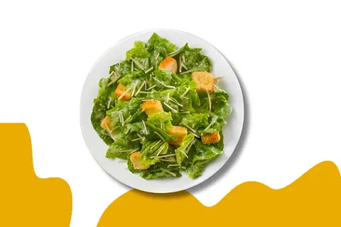 Fresh green salad with lettuce, croutons, and shredded cheese on white plate