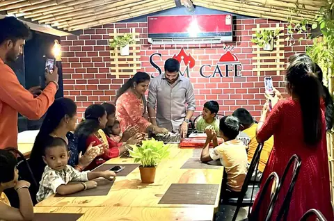Family celebrating with cake inside Sam Cafe, Madurai