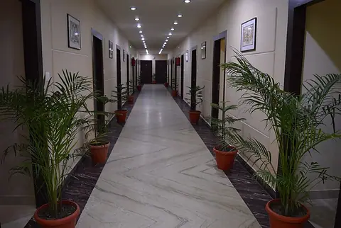 Long corridor with potted plants and framed pictures on walls inside the restaurant