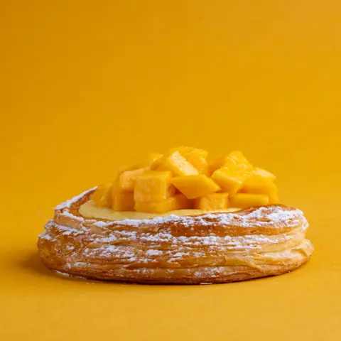 Mango tart with powdered sugar on flaky pastry base