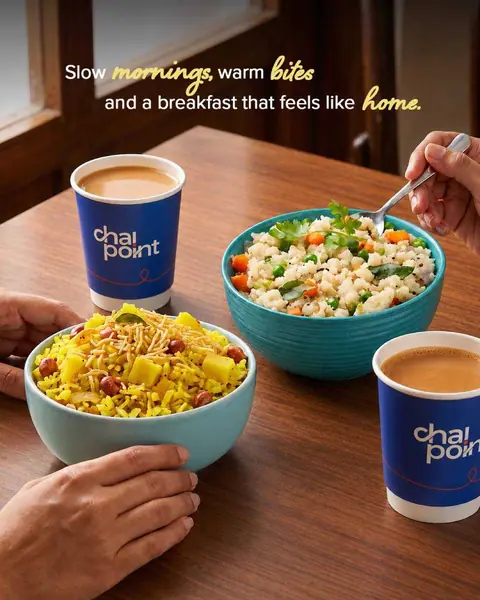 Two bowls of breakfast dishes with two cups of chai on a wooden table
