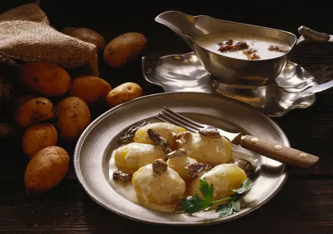 Boiled potatoes garnished with spices and herbs on a metal plate
