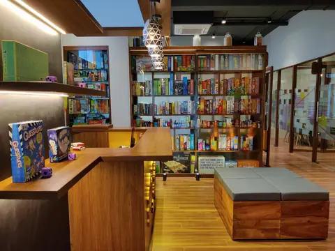 Cozy cafe interior with wooden shelves filled with board games and seating area