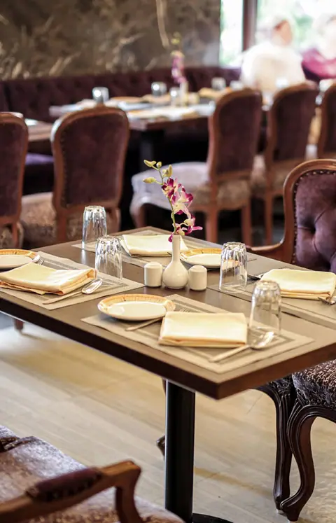 Table set with napkins, glasses, and a flower vase in restaurant interior