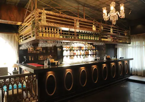 Elegant bar counter with chandelier and bottles at The Avenue restaurant