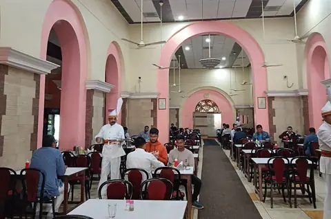 Spacious dining area with pink arches and customers seated at tables