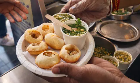 Plate of pani puri with green chutney and fillings