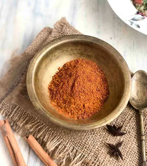 Bowl of red spice powder with cinnamon sticks and star anise