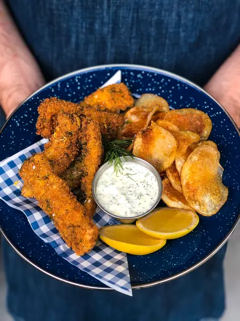Crispy fried chicken strips with potato chips and lemon wedges