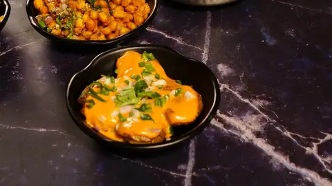 Dish with creamy orange sauce and chopped green herbs in black bowl