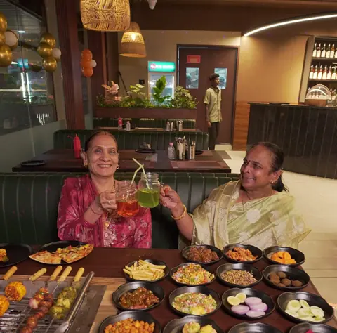 Two women enjoying a variety of grilled dishes and sides at a restaurant table