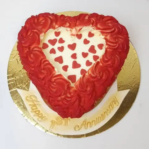 Heart-shaped cake with red frosting and small red hearts on top