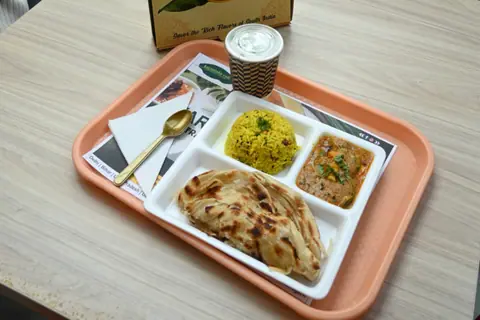 South Indian meal with parotta, yellow rice, curry, and a cup of coffee on tray
