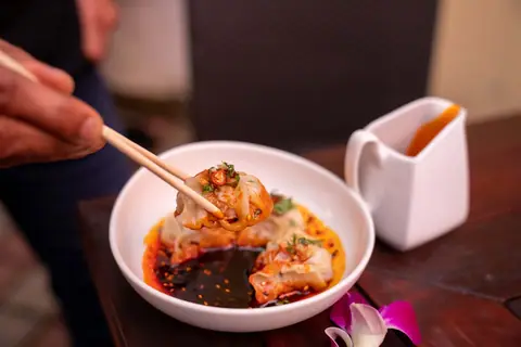 Asian dumplings in spicy red chili oil sauce with dipping sauce