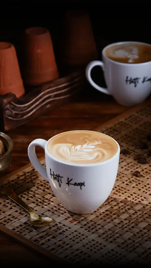 Two cups of latte coffee with latte art in Hatti Kaapi mugs