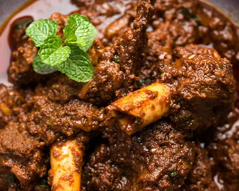 Spicy Indian mutton curry garnished with fresh mint leaves