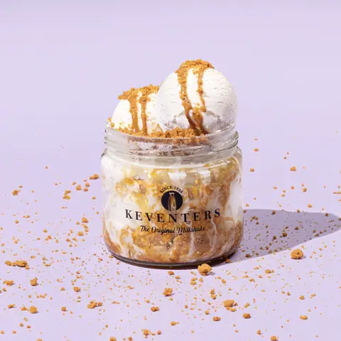 Milkshake topped with two scoops of ice cream and cookie crumbs in a glass jar
