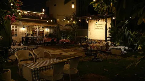 Outdoor seating area of Flourmates Bakery and Cafe at night with tables and chairs