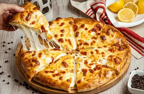 Cheese pizza with melted cheese being pulled from a slice on a wooden board