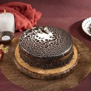 Chocolate cake with decorative chocolate shards on wooden platter