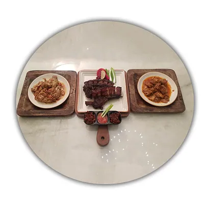 Three dishes with meat and sauces on wooden trays and a marble table