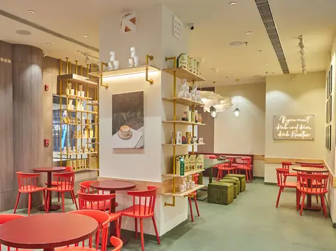 Bright cafe interior with red chairs and wooden shelves displaying items