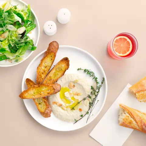 Plate of creamy dip with toasted bread slices and a side salad