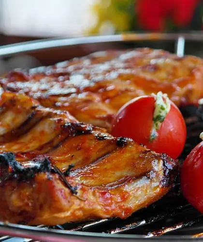 Grilled chicken pieces with roasted tomatoes on a barbecue grill
