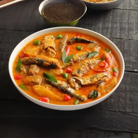 Spicy fish curry with red and green chilies in a white bowl
