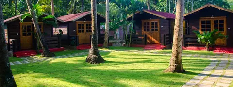 Wooden cottages surrounded by palm trees and green lawn at Brendon restaurant
