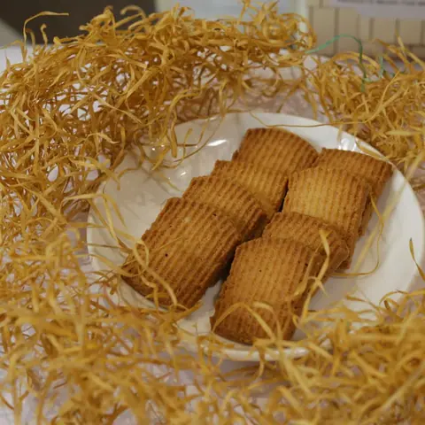Five rectangular brown cookies on a white plate with decorative straw