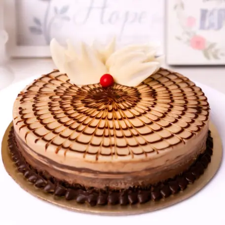 Chocolate layered cake with decorative icing and a cherry on top