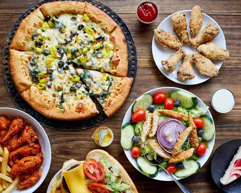 Pizza, fried chicken wings, salad with grilled chicken, and burger with fries