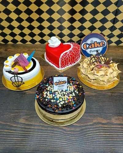 Four decorated cakes including chocolate and heart-shaped red cake on wooden table