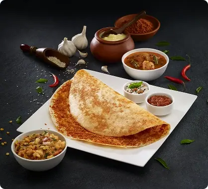 Masala dosa with sambar, chutneys, and potato filling on a white plate