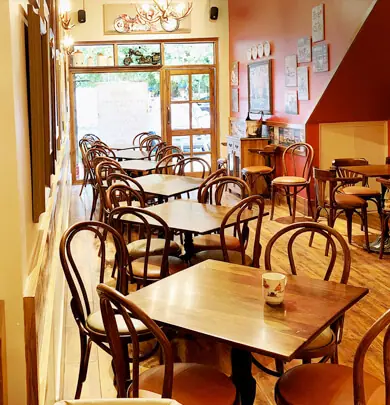Wooden tables and chairs inside Backpackers Cafe with warm lighting