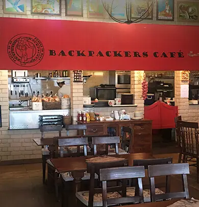 Interior view of Backpackers Cafe with wooden tables and kitchen counter