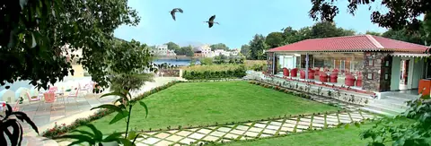 Outdoor seating area with green lawn and lake view at Tribute restaurant