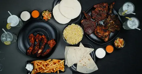 Grilled chicken, biryani, naan, fries, and drinks on a table