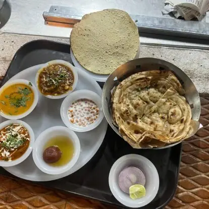 Thali with dal, curry, raita, gulab jamun, papad, roti, onion and lemon