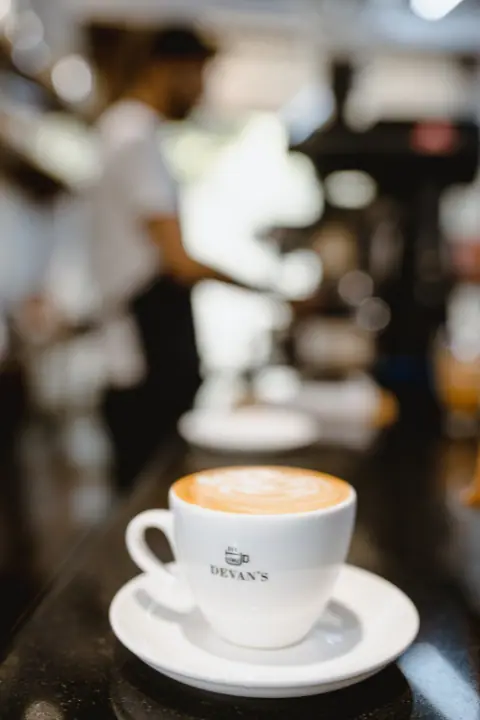 Cup of cappuccino coffee with latte art on a white saucer